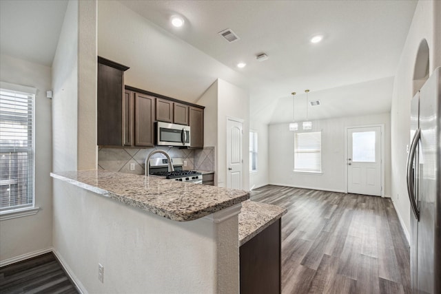 8931 Beacon Mill Dr, Cypress, TX 77433 - kitchen with appliances with stainless steel finishes, decorative backsplash, dark brown cabinetry, light stone counters, and dark wood-style flooring