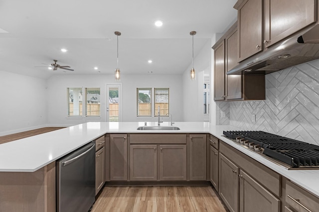 19209 Olive Heath Ln, Magnolia, TX 77355 - kitchen with appliances with stainless steel finishes, a sink, under cabinet range hood, a peninsula, and light wood finished floors