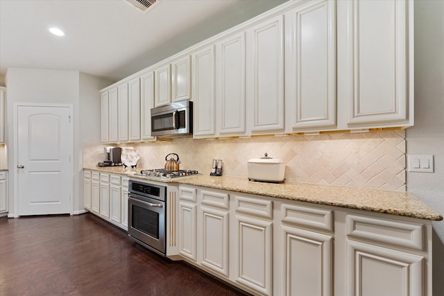12103 Kaiso Ln, Conroe, TX 77304 - kitchen with appliances with stainless steel finishes, tasteful backsplash, dark wood-type flooring, light stone counters, and recessed lighting