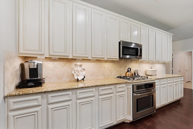 12103 Kaiso Ln, Conroe, TX 77304 - kitchen with appliances with stainless steel finishes, tasteful backsplash, dark wood-style flooring, and white cabinetry