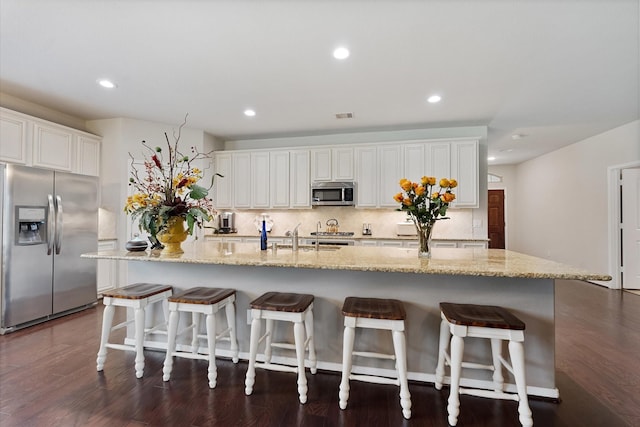12103 Kaiso Ln, Conroe, TX 77304 - kitchen with stainless steel appliances, white cabinets, tasteful backsplash, a large island with sink, and recessed lighting