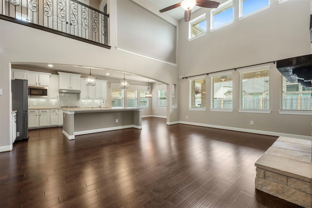 15002 House Martin Ln, Cypress, TX 77429 - unfurnished living room featuring a ceiling fan, a high ceiling, a sink, baseboards, and dark wood-style flooring