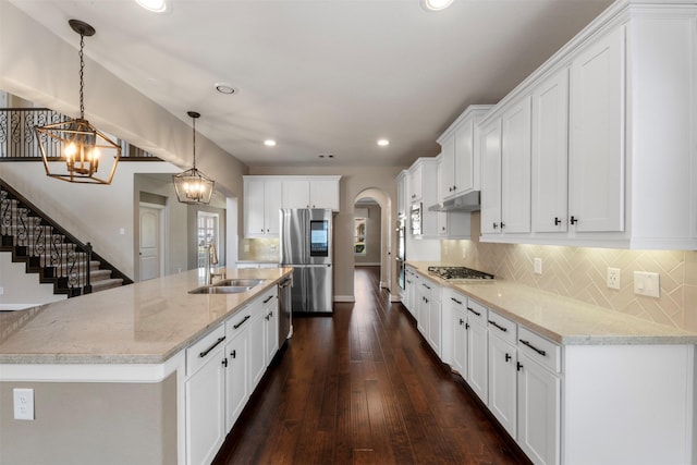 15002 House Martin Ln, Cypress, TX 77429 - kitchen featuring stainless steel appliances, a sink, under cabinet range hood, arched walkways, and white cabinets