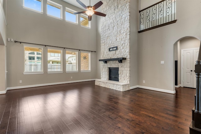 15002 House Martin Ln, Cypress, TX 77429 - unfurnished living room featuring a high ceiling, a ceiling fan, a fireplace, baseboards, and arched walkways