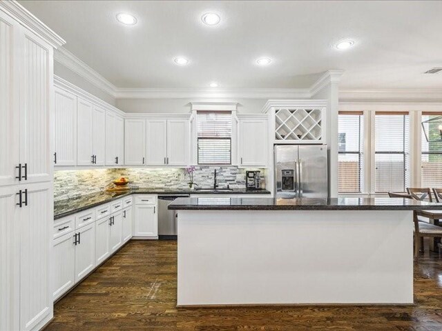 1200 W 24th St, Houston, TX 77008 - kitchen with appliances with stainless steel finishes, ornamental molding, a center island, tasteful backsplash, and white cabinetry