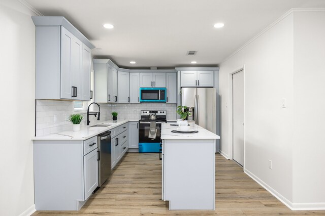 2113 Timber Ln, Conroe, TX 77301 - kitchen with appliances with stainless steel finishes, a sink, a center island, tasteful backsplash, and light wood-style flooring