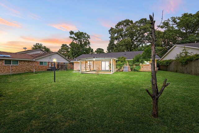 2113 Timber Ln, Conroe, TX 77301 - back of house at dusk featuring central AC, brick siding, and a patio area