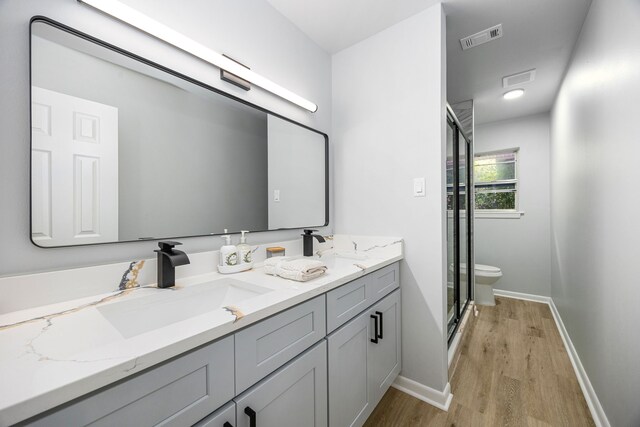 2113 Timber Ln, Conroe, TX 77301 - bathroom with double vanity, a stall shower, wood finished floors, baseboards, and toilet