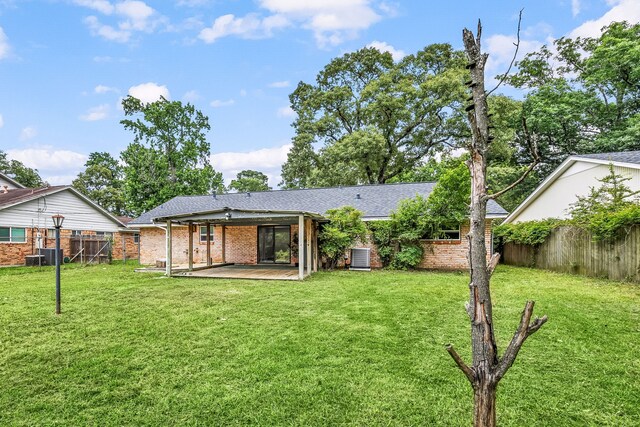 2113 Timber Ln, Conroe, TX 77301 - rear view of property featuring brick siding, a shingled roof, central air condition unit, and a patio area