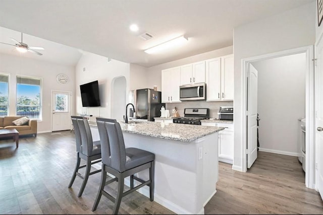 23523 Montague Dr, Spring, TX 77373 - kitchen with stainless steel appliances, a ceiling fan, arched walkways, open floor plan, and wood finished floors
