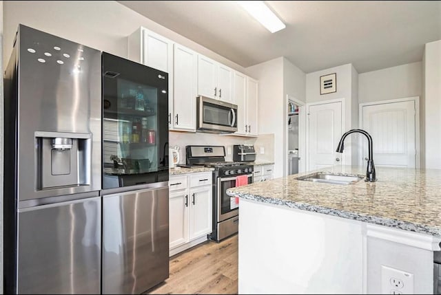 23523 Montague Dr, Spring, TX 77373 - kitchen featuring appliances with stainless steel finishes, a sink, white cabinetry, and light stone counters