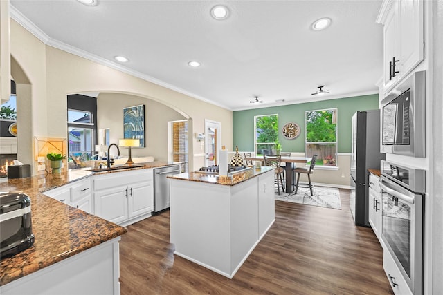 3707 Doyle Ct, Missouri City, TX 77459 - kitchen with stainless steel appliances, a sink, ornamental molding, arched walkways, and white cabinets