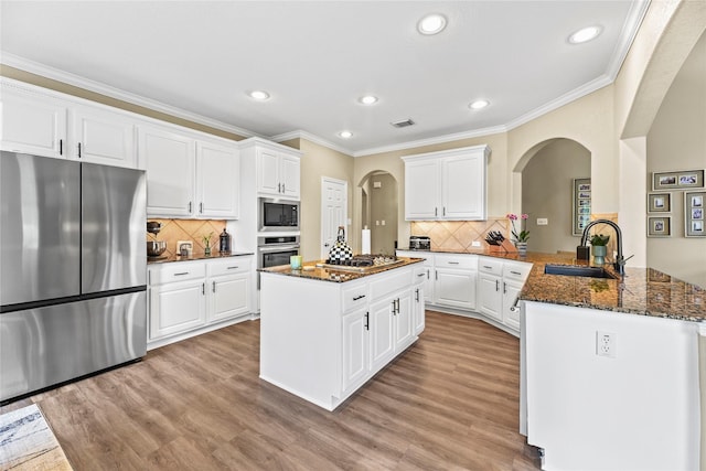 3707 Doyle Ct, Missouri City, TX 77459 - kitchen featuring stainless steel appliances, arched walkways, a sink, a peninsula, and recessed lighting
