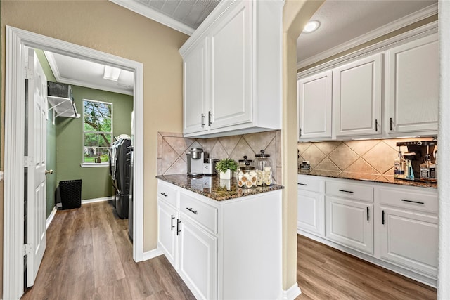 3707 Doyle Ct, Missouri City, TX 77459 - kitchen featuring ornamental molding, light wood-style flooring, dark stone countertops, white cabinetry, and tasteful backsplash