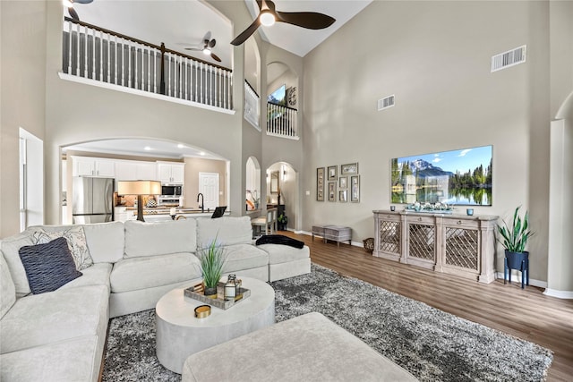 3707 Doyle Ct, Missouri City, TX 77459 - living area featuring arched walkways, a towering ceiling, wood finished floors, a ceiling fan, and baseboards