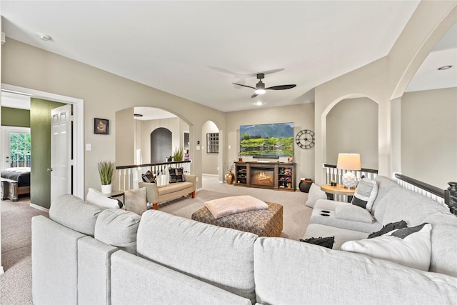 3707 Doyle Ct, Missouri City, TX 77459 - carpeted living room with arched walkways, ceiling fan, a glass covered fireplace, and baseboards