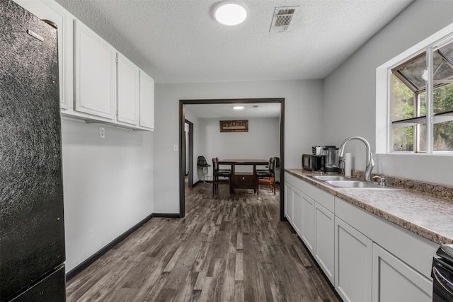 541 Trails End Dr, Cleveland, TX 77328 - kitchen featuring freestanding refrigerator, a sink, dark wood finished floors, white cabinets, and a textured ceiling