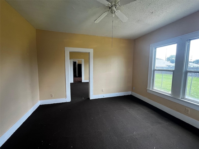 6015 Brady St, Houston, TX 77011 - empty room with baseboards, ceiling fan, dark carpet, and a textured ceiling