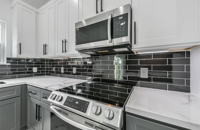 6732 Goforth, Houston, TX 77021 - kitchen featuring stainless steel appliances, gray cabinets, light stone counters, and tasteful backsplash