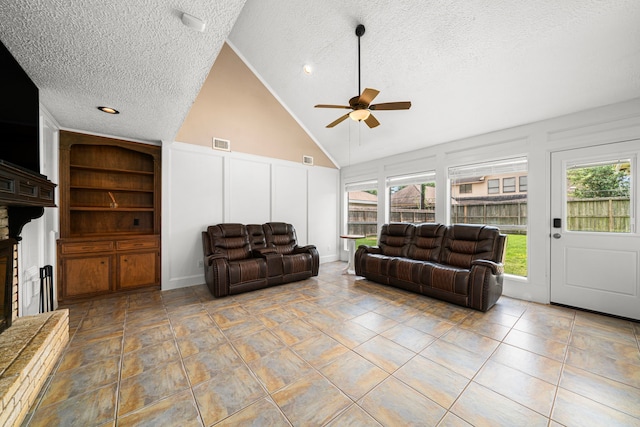 8023 Litchfield Ln, Spring, TX 77379 - living room featuring a decorative wall, a textured ceiling, a ceiling fan, vaulted ceiling, and a fireplace with raised hearth