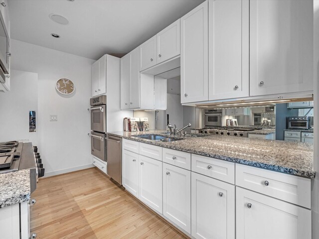 2520 Robinhood St Unit 1012, Houston, TX 77005 - kitchen with stainless steel appliances, light wood-style flooring, a sink, and white cabinetry