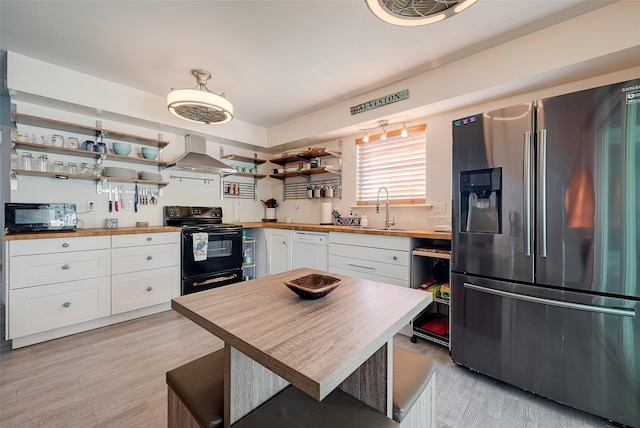 1717 22nd St, Galveston, TX 77550 - kitchen with butcher block countertops, black appliances, open shelves, and wall chimney range hood