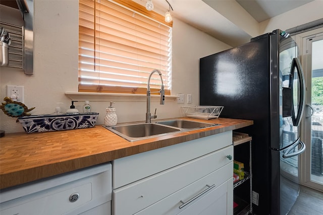 1717 22nd St, Galveston, TX 77550 - kitchen with butcher block countertops, a sink, freestanding refrigerator, dishwashing machine, and white cabinetry