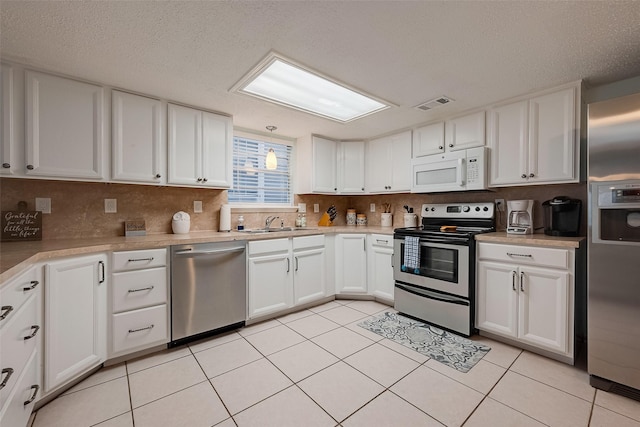 1717 22nd St, Galveston, TX 77550 - kitchen with appliances with stainless steel finishes, a sink, white cabinets, backsplash, and light tile patterned flooring