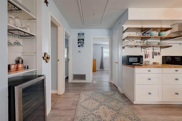 1717 22nd St, Galveston, TX 77550 - kitchen featuring black microwave, wine cooler, white cabinetry, open shelves, and light wood-type flooring