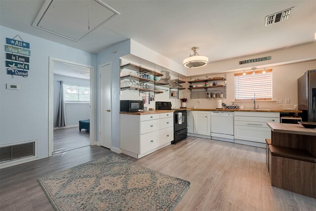 1717 22nd St, Galveston, TX 77550 - kitchen featuring black appliances, open shelves, white cabinetry, and light wood-style floors