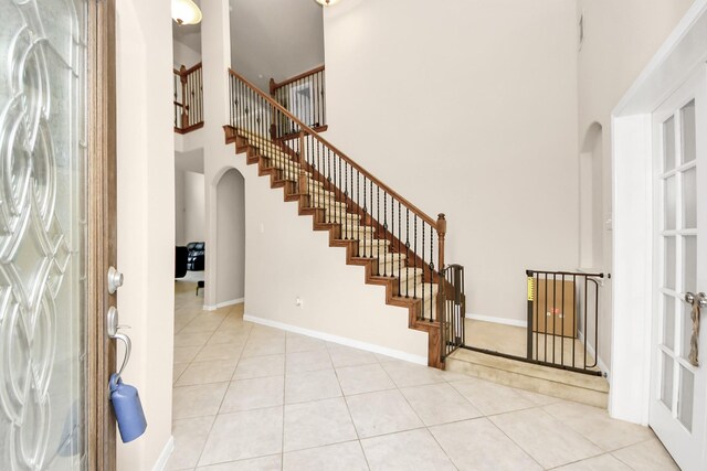 3922 Crestwind Ln, Richmond, TX 77407 - tiled foyer with arched walkways, a towering ceiling, stairway, and baseboards