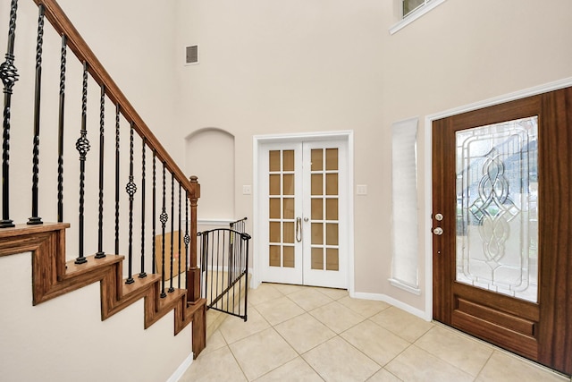 3922 Crestwind Ln, Richmond, TX 77407 - entrance foyer with french doors, a towering ceiling, light tile patterned floors, baseboards, and stairway