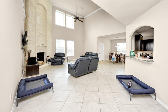 3922 Crestwind Ln, Richmond, TX 77407 - living area with a ceiling fan, a stone fireplace, light tile patterned floors, a towering ceiling, and baseboards