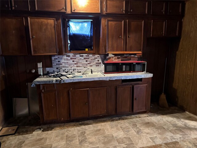 4204 Wipprecht St, Houston, TX 77026 - kitchen featuring stone finish floors, a sink, light countertops, backsplash, and dark brown cabinetry