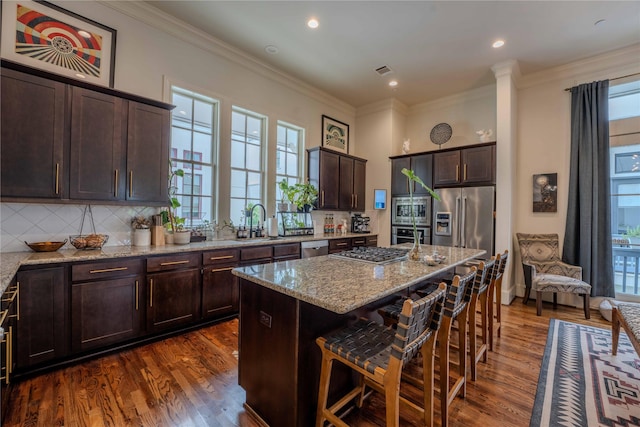 242 E 28th St, Houston, TX 77008 - kitchen with stainless steel appliances, dark brown cabinetry, a sink, light stone countertops, and decorative backsplash