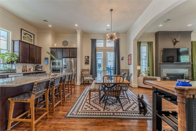 242 E 28th St, Houston, TX 77008 - dining area with healthy amount of natural light, ornamental molding, arched walkways, wood finished floors, and a glass covered fireplace
