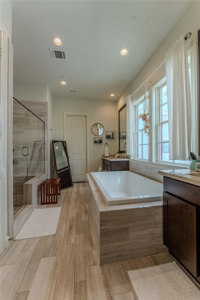 242 E 28th St, Houston, TX 77008 - bathroom featuring vanity, a bath, a shower stall, recessed lighting, and wood finished floors