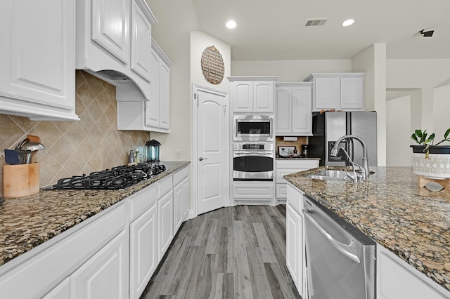 16819 Talisker Dr, Richmond, TX 77407 - kitchen with appliances with stainless steel finishes, a sink, white cabinets, dark stone countertops, and recessed lighting