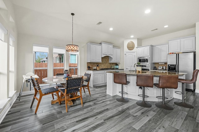 16819 Talisker Dr, Richmond, TX 77407 - kitchen featuring appliances with stainless steel finishes, wood finished floors, decorative backsplash, recessed lighting, and white cabinets