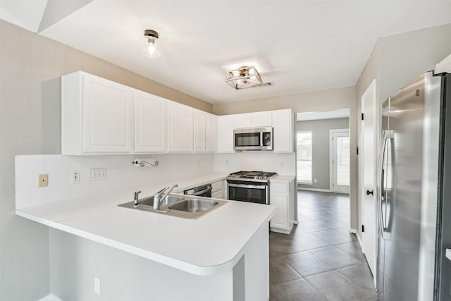2318 Old Oak Ln, Kingwood, TX 77339 - kitchen featuring appliances with stainless steel finishes, a sink, a peninsula, and white cabinetry