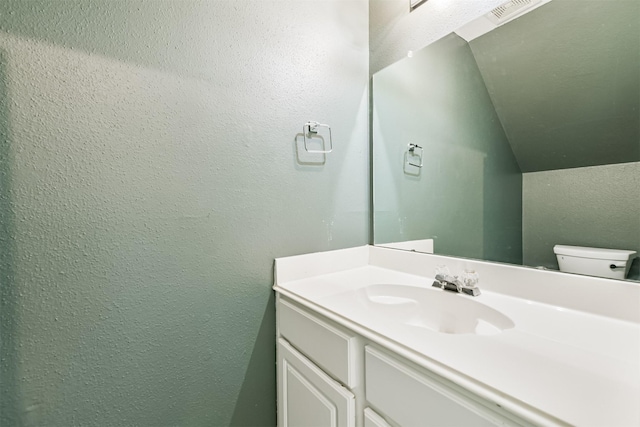 2318 Old Oak Ln, Kingwood, TX 77339 - half bathroom with vanity, a textured wall, toilet, and lofted ceiling