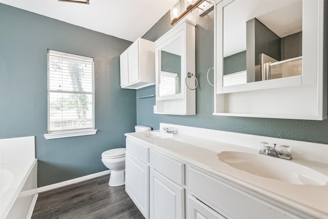2318 Old Oak Ln, Kingwood, TX 77339 - full bathroom featuring double vanity, toilet, a garden tub, wood finished floors, and baseboards