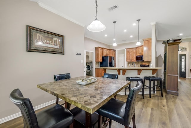 18024 Cindy Ln, Conroe, TX 77302 - dining space with washer / dryer, crown molding, light wood-style flooring, baseboards, and recessed lighting