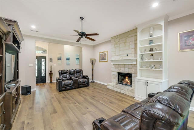 18024 Cindy Ln, Conroe, TX 77302 - living room featuring a ceiling fan, a fireplace, light wood-style flooring, ornamental molding, and baseboards