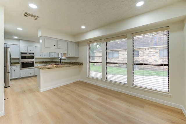 1715 Cobblestone Ct, Richmond, TX 77406 - kitchen featuring appliances with stainless steel finishes, a peninsula, recessed lighting, baseboards, and light wood finished floors