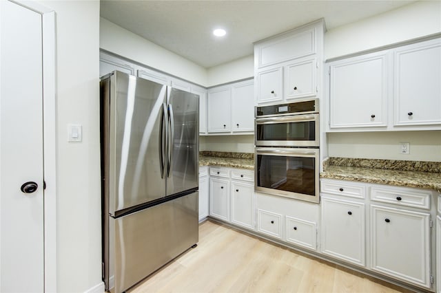 1715 Cobblestone Ct, Richmond, TX 77406 - kitchen featuring stainless steel appliances, light wood-type flooring, white cabinets, light stone counters, and recessed lighting