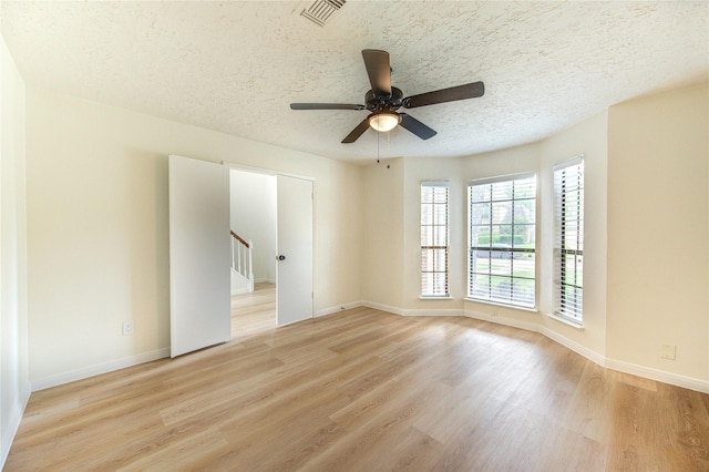 1715 Cobblestone Ct, Richmond, TX 77406 - spare room featuring light wood-style flooring, baseboards, ceiling fan, a textured ceiling, and stairs