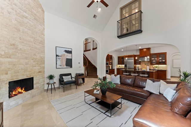 82 Valera Ridge Dr, Spring, TX 77389 - living area with arched walkways, ceiling fan, high vaulted ceiling, a fireplace, and stairway