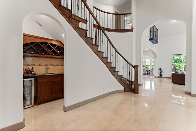 82 Valera Ridge Dr, Spring, TX 77389 - stairway with wine cooler, a high ceiling, wet bar, baseboards, and arched walkways