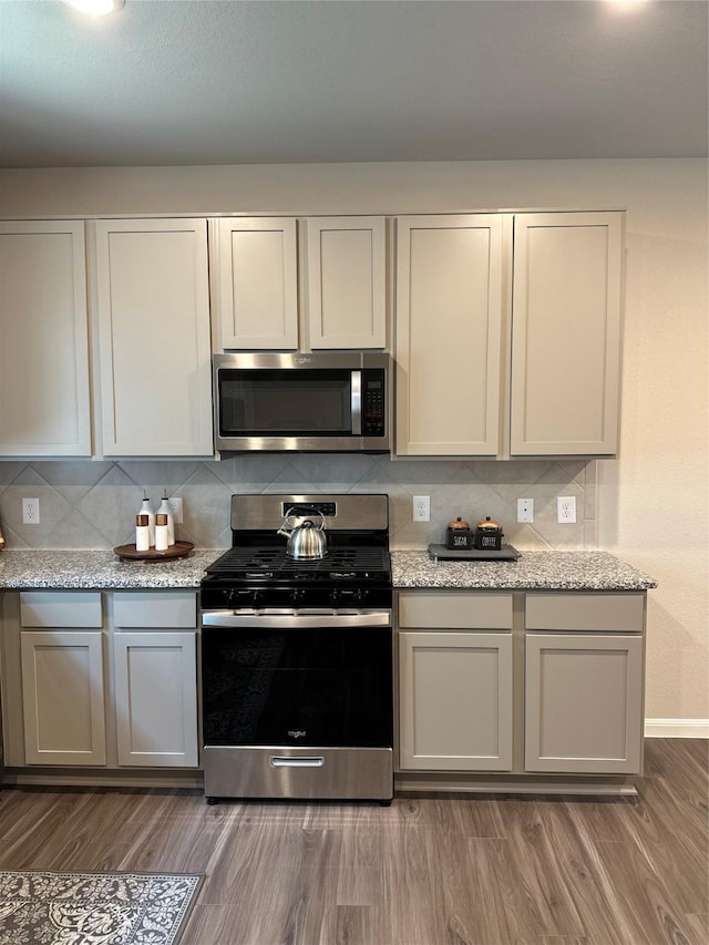 13556 Bowfin Dr, Conroe, TX 77384 - kitchen with appliances with stainless steel finishes, backsplash, wood finished floors, and baseboards